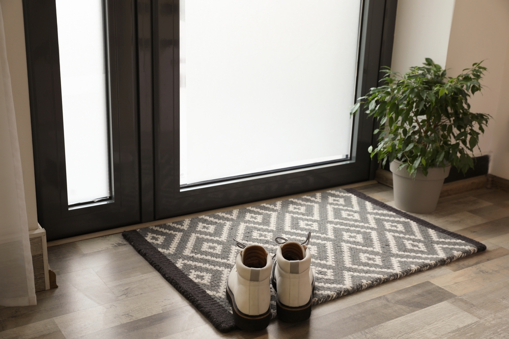 Stylish boots in contemporary home, resting on welcome mat.
